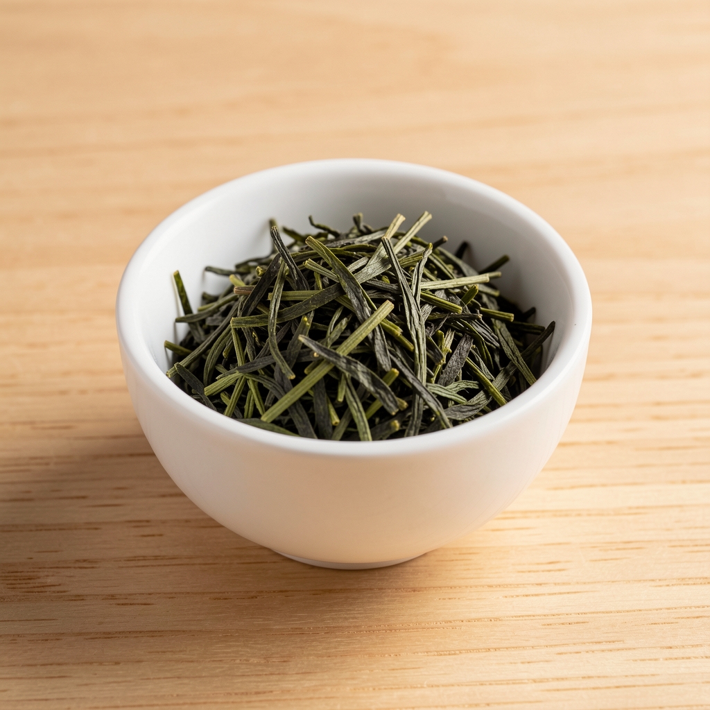 Hojas finas de té verde Sencha en un cuenco de cerámica blanca sobre mesa de madera clara
